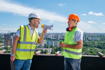 Angry boss yelling in megaphone at his builder because he made mistake on construction on the urban...