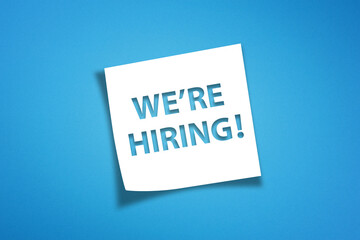 We are hiring written white note paper on blue background, recruitment concept