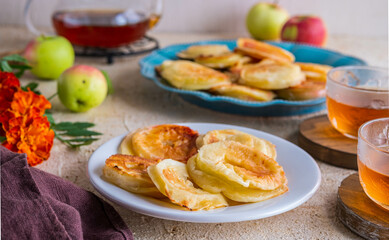 Dessert, fried rings of apples in batter on a white plate on a light concrete background. Apples recipes.