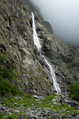 Midagrabin waterfall in sunlight in cloudy summer weather. Caucasus mountains. Russia. North Ossetia Alania