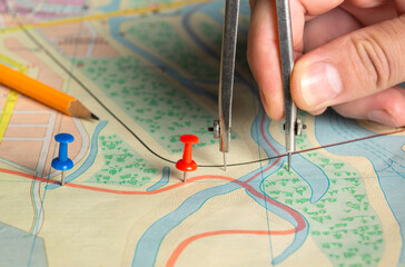 The surveyor marks the distance on the map with red buttons. Close-up of a surveyor's hand with a...
