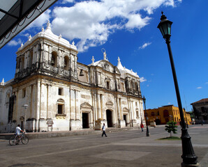 Obraz premium Leon, Nicaragua, cathedral in the main square of Leon. Blue sky, sunny with clouds, street scene with people walking and bicycle
