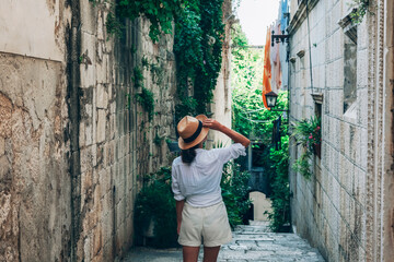 Girl tourist walking through ancient narrow streets on a beautiful summer day in Korcula, Croatia