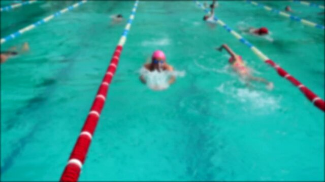 Swimming pool training. Athletes practice swimming technique. Out of focus.