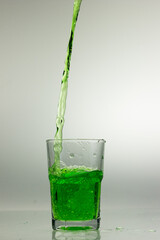 Studio shot of green liquid poured into clear glass isolated