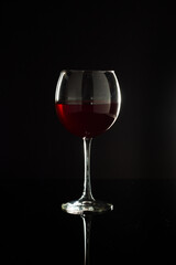 A studio shot of an elegant, isolated wine glass on black with reflections