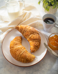 French breakfast - two croissants, orange jam and a cup of black coffee. on a white silk tablecloth. Restaurant, hotel and advertising business. Home cooking, recipe book.