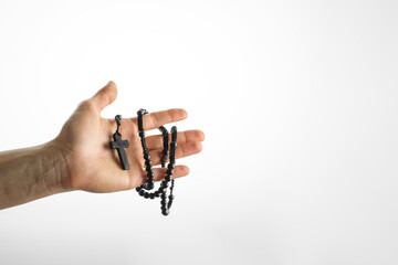 Rosary and crucifix in a woman's hand. Simple white background. Minimalism. Christianity. Catholicism, faith, spirituality, meditation. Empty space to insert.