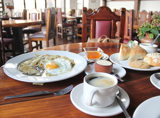 Delicious Mexican breakfast with coffee, sweet bread, beans, chilaquiles, butter, jam, sugar, fried egg, omelette
