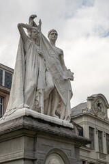 Naklejka premium Gent, Flanders, Belgium - July 30, 2021: Closeup of male-female combination white statue on pedestal to honor Jan-Frans Willems against white cloudscape, in front of NTG theater.