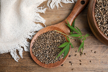 Organic hemp seeds and leaves on wooden table, flat lay