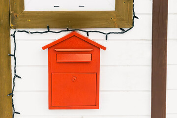 White wooden house of Santa Claus artificial structure with red post mail box for letters from kids children in winter snowy city park close up. Christmas xmas new year holiday concept