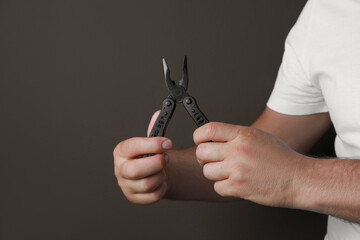 Man holding multitool on brown background, closeup