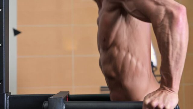 Close up of a Muscular man doing triceps dip on parallel bars in gym. High quality 4k footage