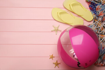 Flat lay composition with beach ball on pink wooden background. Space for text
