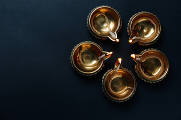 Lit diyas on dark background, flat lay with space for text. Diwali lamps