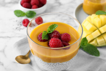 Delicious chia pudding with mango sauce and raspberries on table, closeup