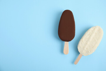 Glazed ice cream bars on light blue background, flat lay. Space for text