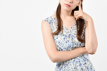 白い背景の前で悩んでいる私服姿の若い女性