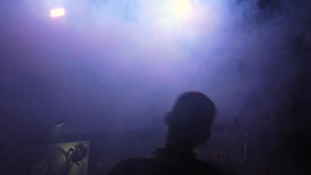 Disc Jockey Playing and Mixing Records With Smoke In the Sunset. Close up drone view over the Dj.