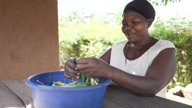Local African black woman smiling, peeling and cooking red kidney beans. Preparing traditional African food. Africa 4K.