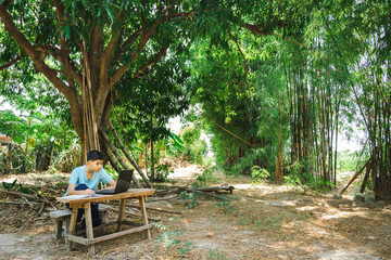 A boy concentrates on studying online with a laptop computer at home in the countryside