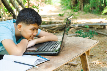 The boy happily focused on studying online with his laptop computer at home in the country