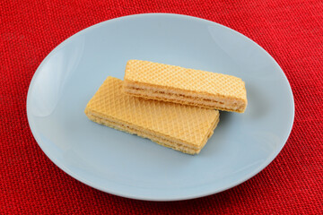 Two taro cream wafer cookies on blue snack plate on red background