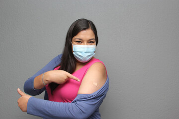 Latino adult woman shows her arm that just received the Covid-19 vaccine in the new normal for the...