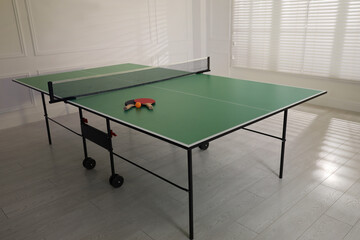 Rackets and ball on ping pong table indoors