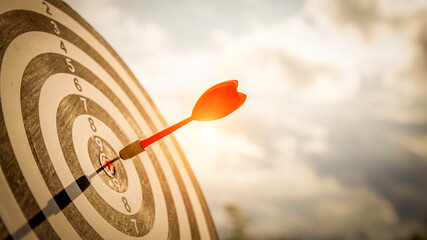 Close up shot red darts arrows in the target  of dartboard center on dark blue sky background....