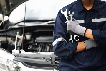 Hand of car mechanic with wrench. Auto repair garage. mechanic works on the engine of the car in...