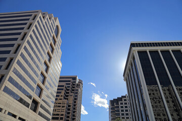 Tall business buildings are shown from a street level view during the day.