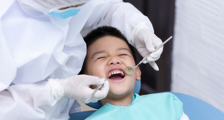 Dentist examining Asian little boy teeth in the clinic. Calm and happy