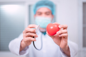 Doctor holding heart and smiling at camera, health view