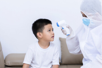 Doctor measuring temperature little child boy with infrared thermometer