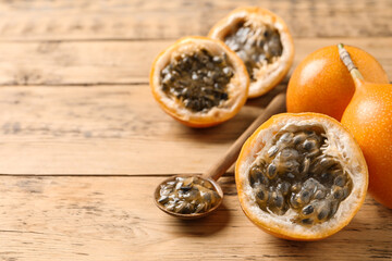 Delicious ripe granadillas on wooden table, space for text