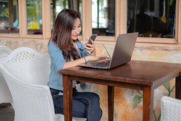 Young Asian woman using laptop computer and tablet PC to working in the modern co working space	
