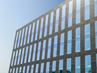 facade of a modern office building on a bright sunny day with windows reflecting the sky