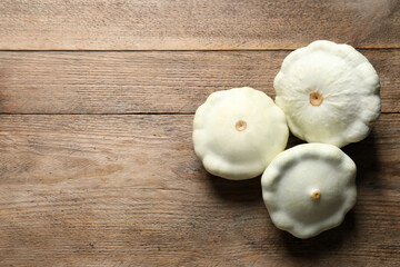 Fresh ripe white pattypan squashes on wooden table, flat lay. Space for text