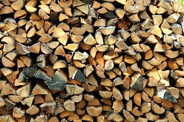 The ends of chopped birch firewood stacked in a woodpile 