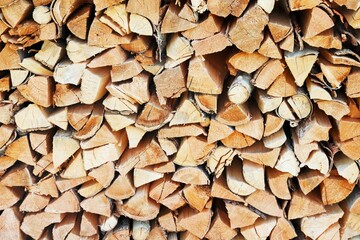 The ends of chopped birch firewood stacked in a woodpile 