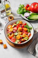 Tuscan Panzanella, traditional Italian salad with tomatoes and toasted bread. Vegetarian panzanella salad. Light gray background.