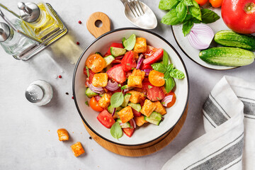 Tuscan Panzanella, traditional Italian salad with tomatoes and toasted bread. Vegetarian panzanella salad. Light gray background. Top view
