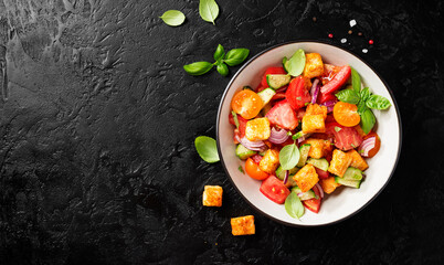 Tuscan Panzanella, traditional Italian salad with tomatoes and toasted bread. Vegetarian panzanella salad.Black background. Top view