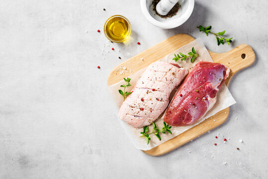 Preparation for cooking raw duck breast with ingredients. Light gray background, top view. Space for text