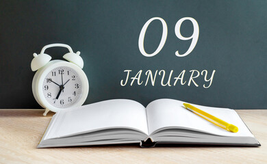 january 09. 09-th day of the month, calendar date.A white alarm clock, an open notebook with blank pages, and a yellow pencil lie on the table.Winter month, day of the year concept