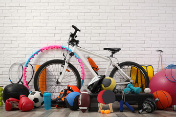 Bicycle and different sport equipment near white brick wall