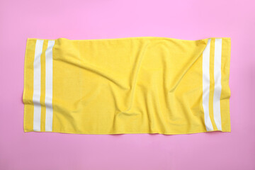 Fototapeta na wymiar Crumpled yellow beach towel on pink background, top view