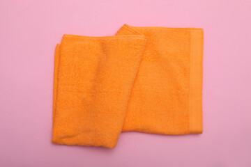 Folded orange beach towel on pink background, top view